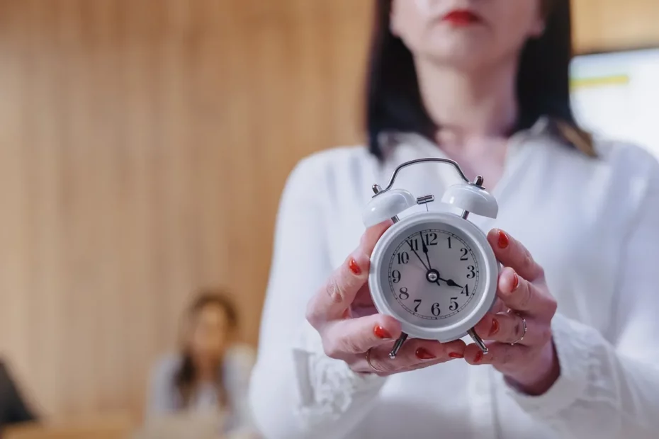 Mulher segurando um relógio analógico branco em destaque, simbolizando a importância da gestão do tempo em um ambiente de trabalho.