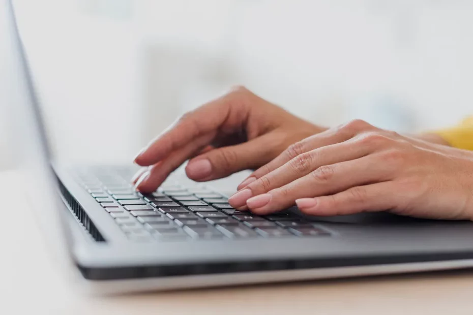 Mãos femininas digitando em um notebook moderno com teclado preto, transmitindo concentração e produtividade.